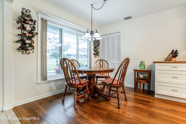 dining space with baseboards, light wood-type flooring, visible vents, and a notable chandelier