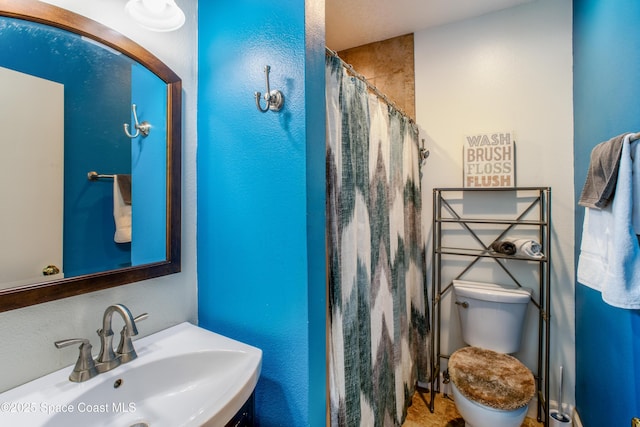 full bathroom with curtained shower, a sink, and toilet