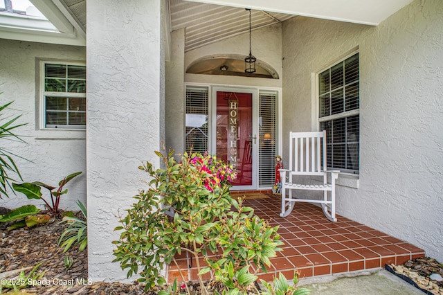 property entrance with a porch and stucco siding