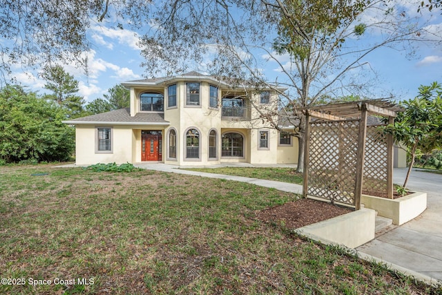 view of front of home with stucco siding, concrete driveway, a front yard, a balcony, and a pergola