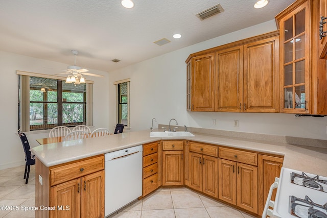 kitchen with a peninsula, a sink, visible vents, dishwasher, and gas range oven