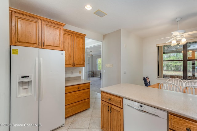 kitchen with light countertops, white appliances, light tile patterned flooring, and brown cabinets