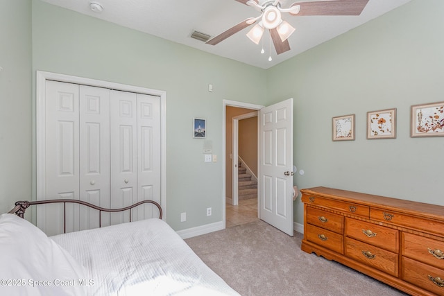 bedroom featuring a closet, light colored carpet, visible vents, a ceiling fan, and baseboards