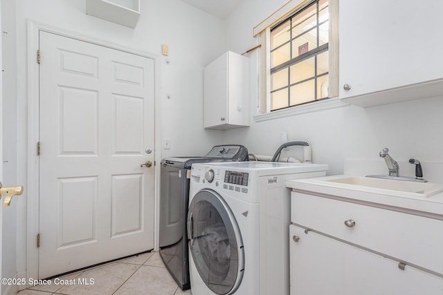 laundry room featuring cabinet space, washing machine and dryer, a sink, and light tile patterned flooring