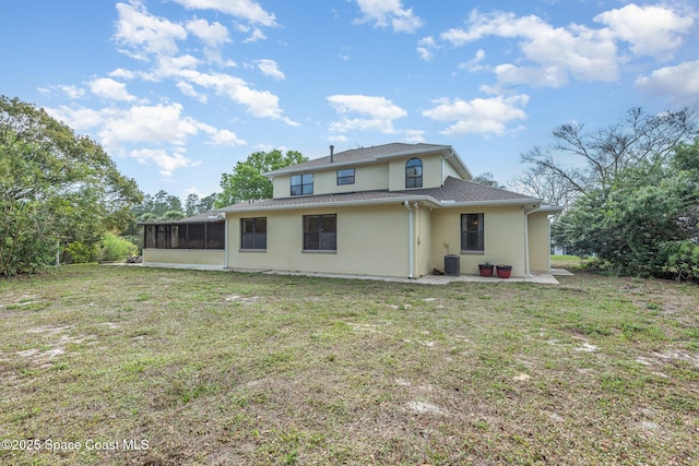 rear view of property with a sunroom, central AC unit, stucco siding, and a yard