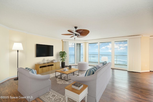 living area featuring a textured ceiling, crown molding, baseboards, and wood finished floors