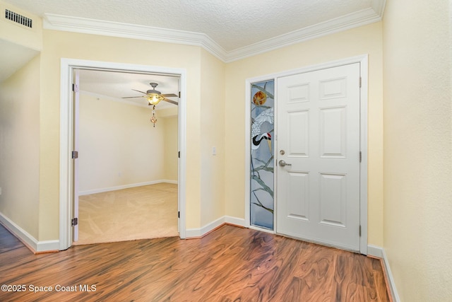 entrance foyer featuring baseboards, visible vents, dark wood-style flooring, a textured ceiling, and crown molding