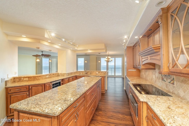 kitchen featuring brown cabinets, backsplash, a kitchen island, wine cooler, and black electric cooktop