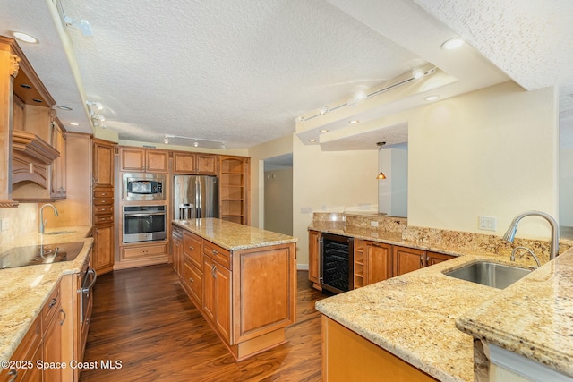 kitchen featuring brown cabinetry, beverage cooler, light stone countertops, a sink, and stainless steel appliances