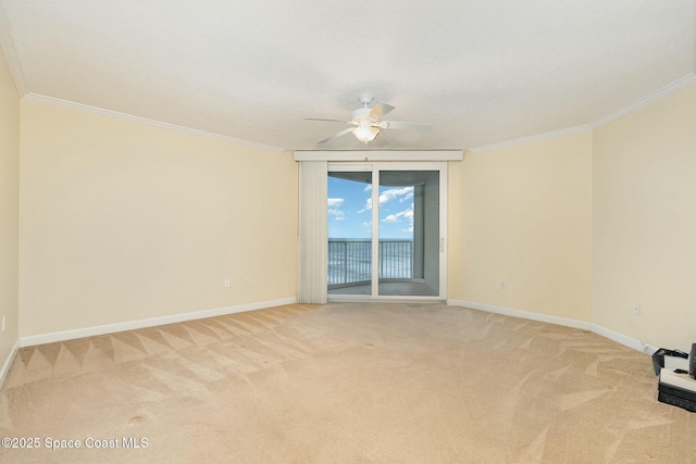 unfurnished room featuring ceiling fan, crown molding, baseboards, and light carpet