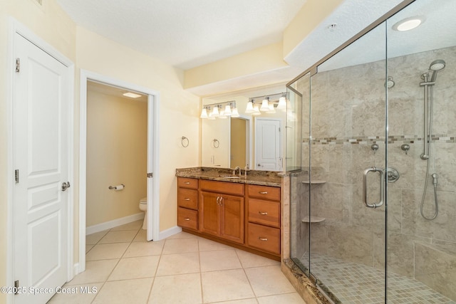 bathroom featuring a shower stall, baseboards, toilet, tile patterned floors, and vanity