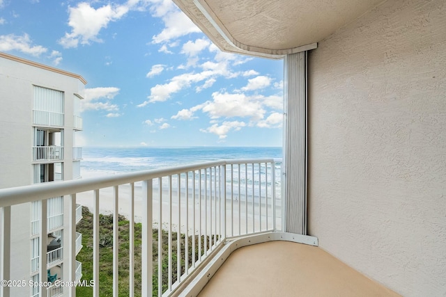 balcony featuring a view of the beach and a water view