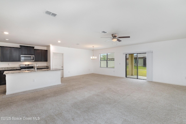 unfurnished living room with a sink, a ceiling fan, light colored carpet, a chandelier, and recessed lighting