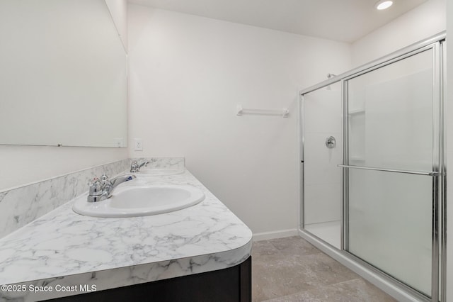 full bathroom with a shower stall, baseboards, and double vanity