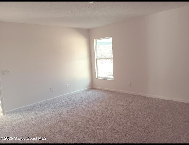 spare room featuring carpet floors, a textured ceiling, and baseboards