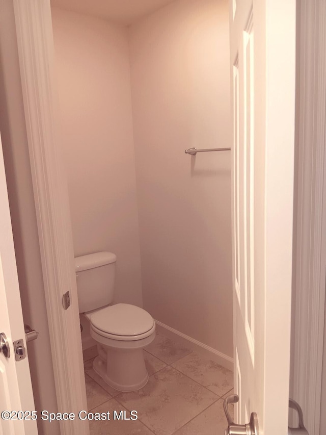 bathroom with toilet, tile patterned flooring, and baseboards