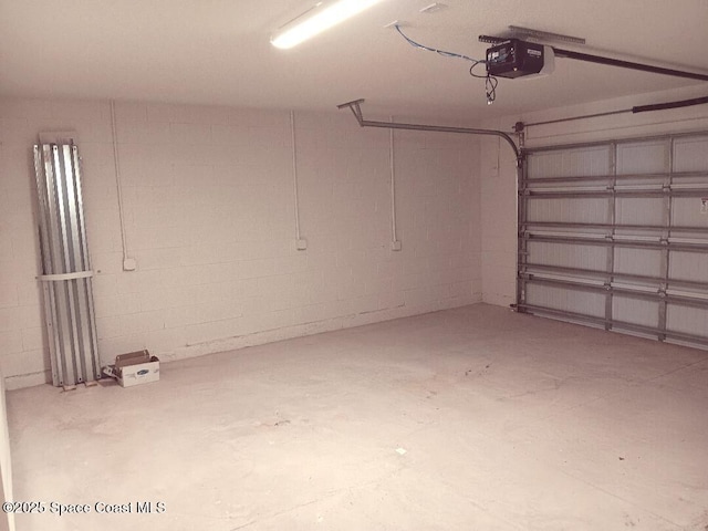 garage with a garage door opener and concrete block wall