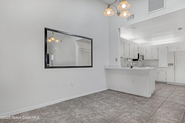 kitchen with white cabinetry, white fridge with ice dispenser, visible vents, and light countertops