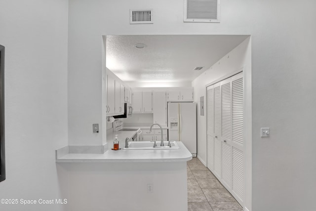 kitchen with white refrigerator with ice dispenser, stove, a sink, visible vents, and light countertops