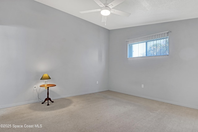 carpeted spare room with a textured ceiling, baseboards, and a ceiling fan