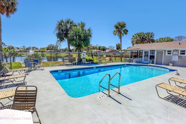 pool featuring a patio, a water view, and fence