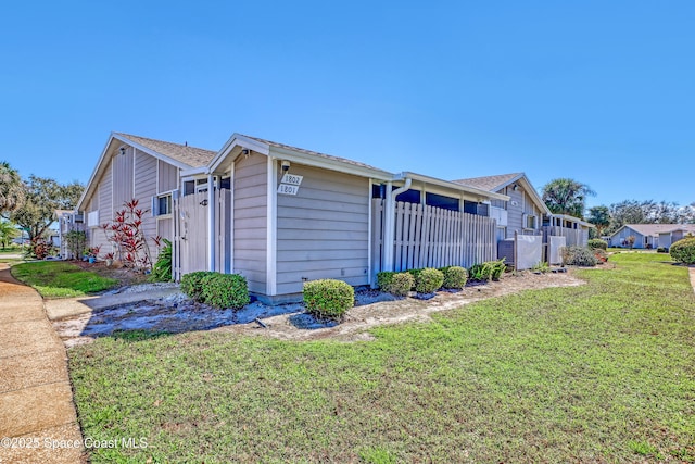 view of property exterior with fence and a lawn