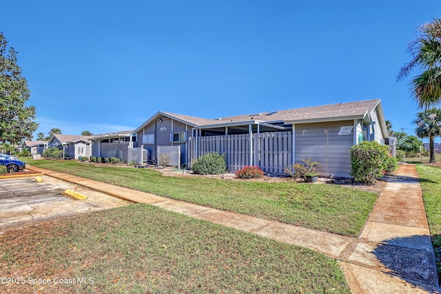 view of front of house with uncovered parking, a front lawn, and fence