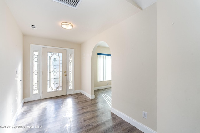 entrance foyer with baseboards, visible vents, arched walkways, and wood finished floors