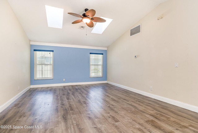 spare room featuring vaulted ceiling with skylight, a healthy amount of sunlight, and ceiling fan