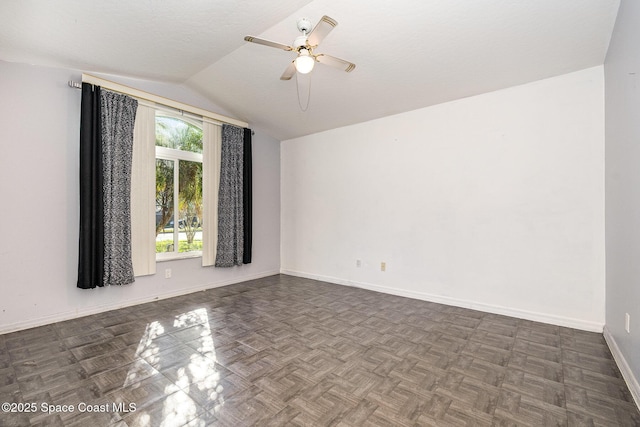 empty room featuring a ceiling fan, vaulted ceiling, and baseboards