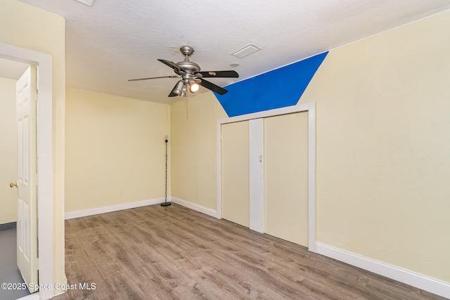 unfurnished bedroom featuring baseboards, a textured ceiling, visible vents, and wood finished floors