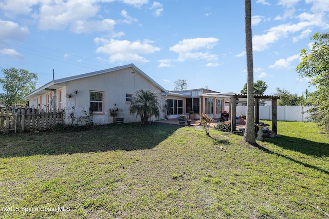 rear view of house with a sunroom, a patio area, a lawn, and a fenced backyard