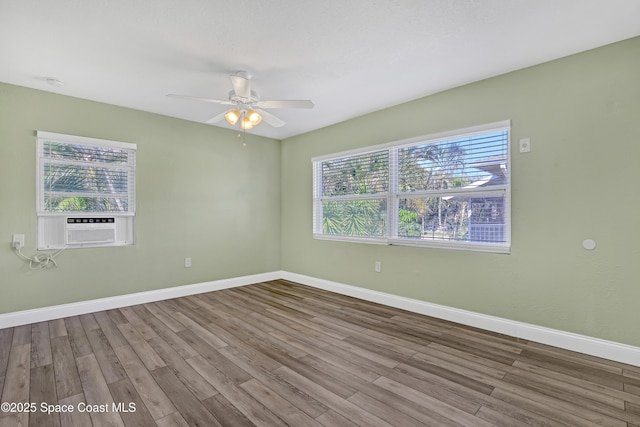 unfurnished room with cooling unit, plenty of natural light, wood finished floors, and baseboards