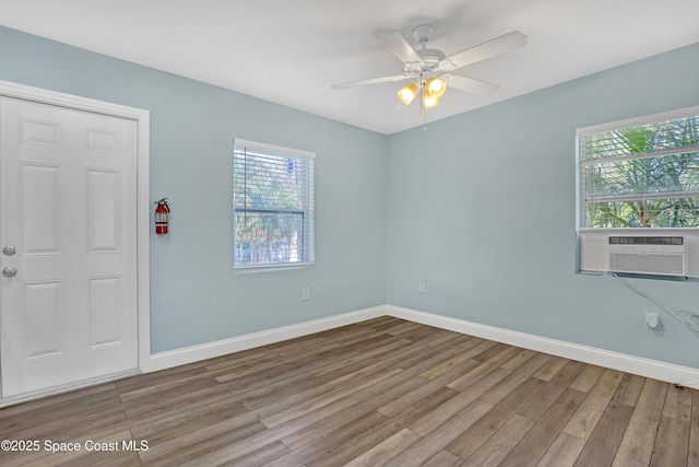 spare room featuring cooling unit, wood finished floors, and baseboards