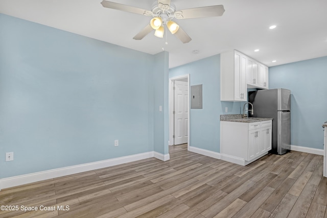 kitchen featuring light wood-style flooring, white cabinetry, and baseboards