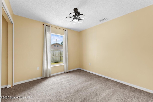 spare room with a textured ceiling, carpet, visible vents, and baseboards