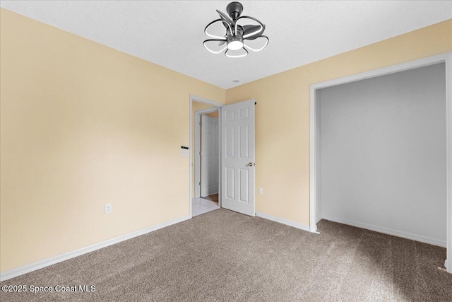 unfurnished bedroom with carpet flooring, a textured ceiling, and baseboards