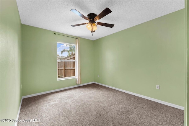 empty room with a textured ceiling, carpet floors, a ceiling fan, and baseboards