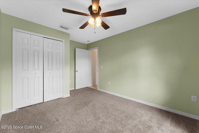 unfurnished bedroom featuring a textured ceiling, visible vents, baseboards, a closet, and carpet