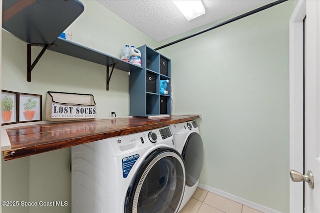 laundry area featuring light tile patterned floors, a textured ceiling, laundry area, independent washer and dryer, and baseboards