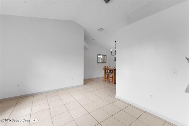 spare room featuring lofted ceiling, light tile patterned floors, a textured ceiling, and baseboards