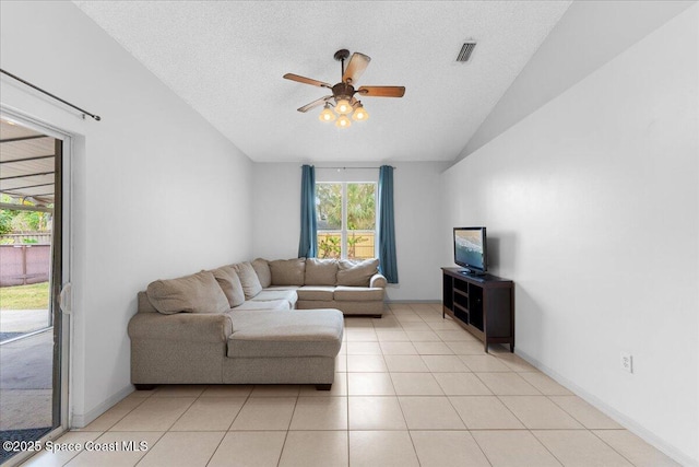 living area with lofted ceiling, visible vents, a ceiling fan, light tile patterned flooring, and a textured ceiling