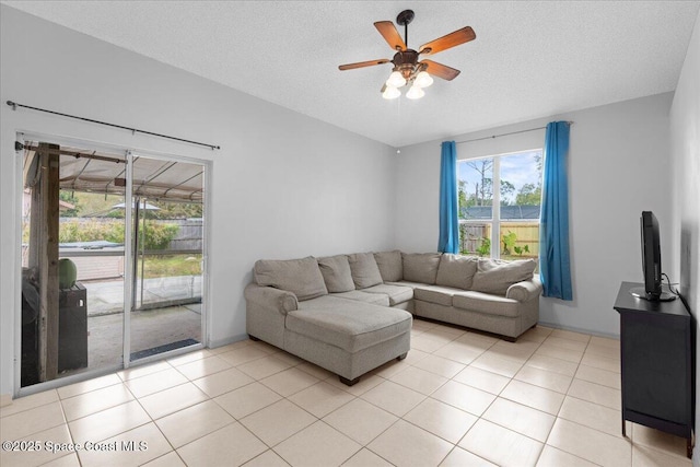 living room featuring a ceiling fan, lofted ceiling, a textured ceiling, and light tile patterned floors