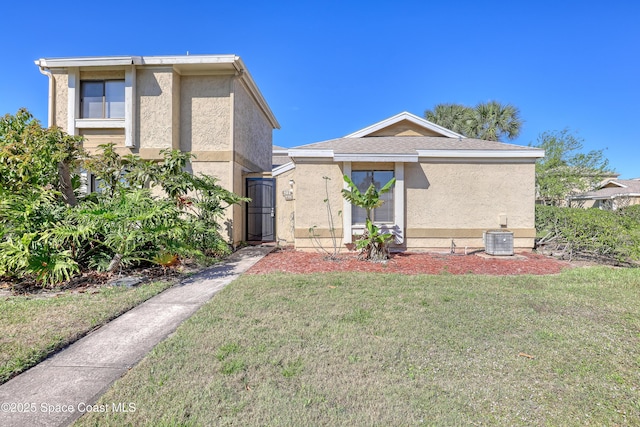 view of front of home featuring central air condition unit, a front lawn, and stucco siding