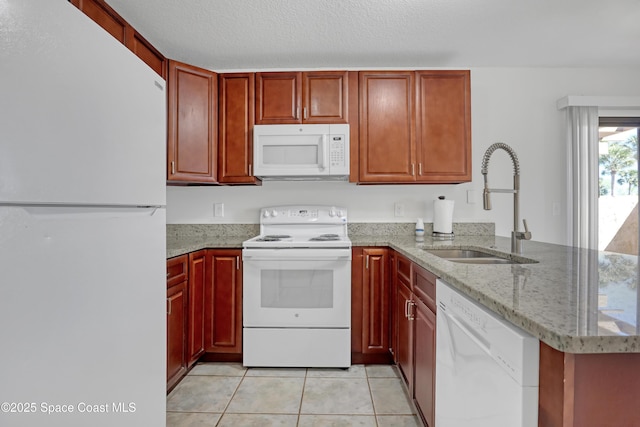 kitchen featuring light tile patterned floors, a peninsula, white appliances, a sink, and dark brown cabinets