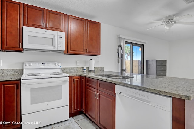 kitchen with light tile patterned flooring, a peninsula, white appliances, a sink, and reddish brown cabinets