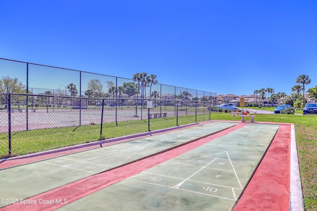 surrounding community featuring shuffleboard, fence, and a lawn