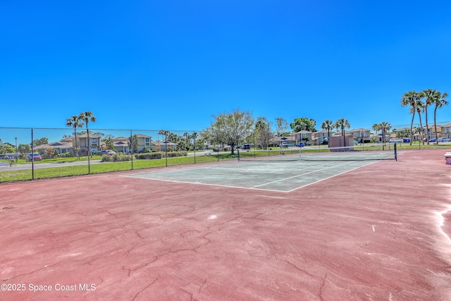 view of tennis court featuring fence and a residential view