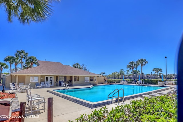 community pool with a patio area and fence