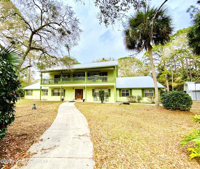 view of front of house with metal roof, a balcony, and stucco siding